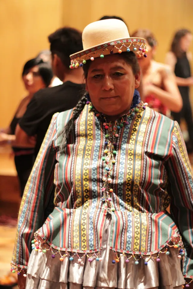 Retrato de una participante con sombrero y una prenda de colores.