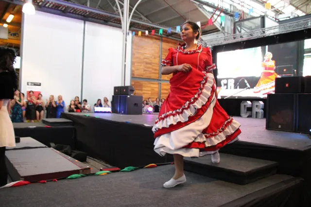 Una participante desfila con un vestido rojo con volados blancos.
