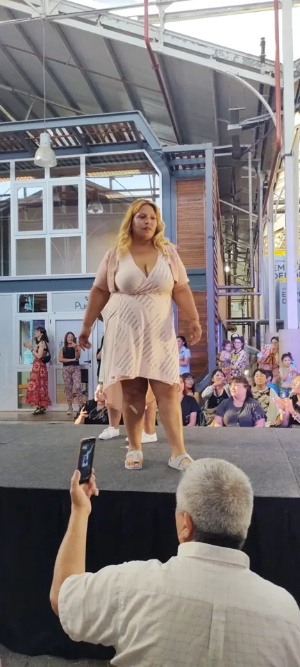 Una participante desfila con un vestido claro frente al público.