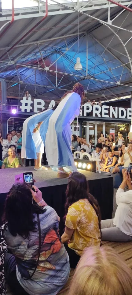 Una prenda celeste y blanca se despliega en movimiento sobre el escenario.